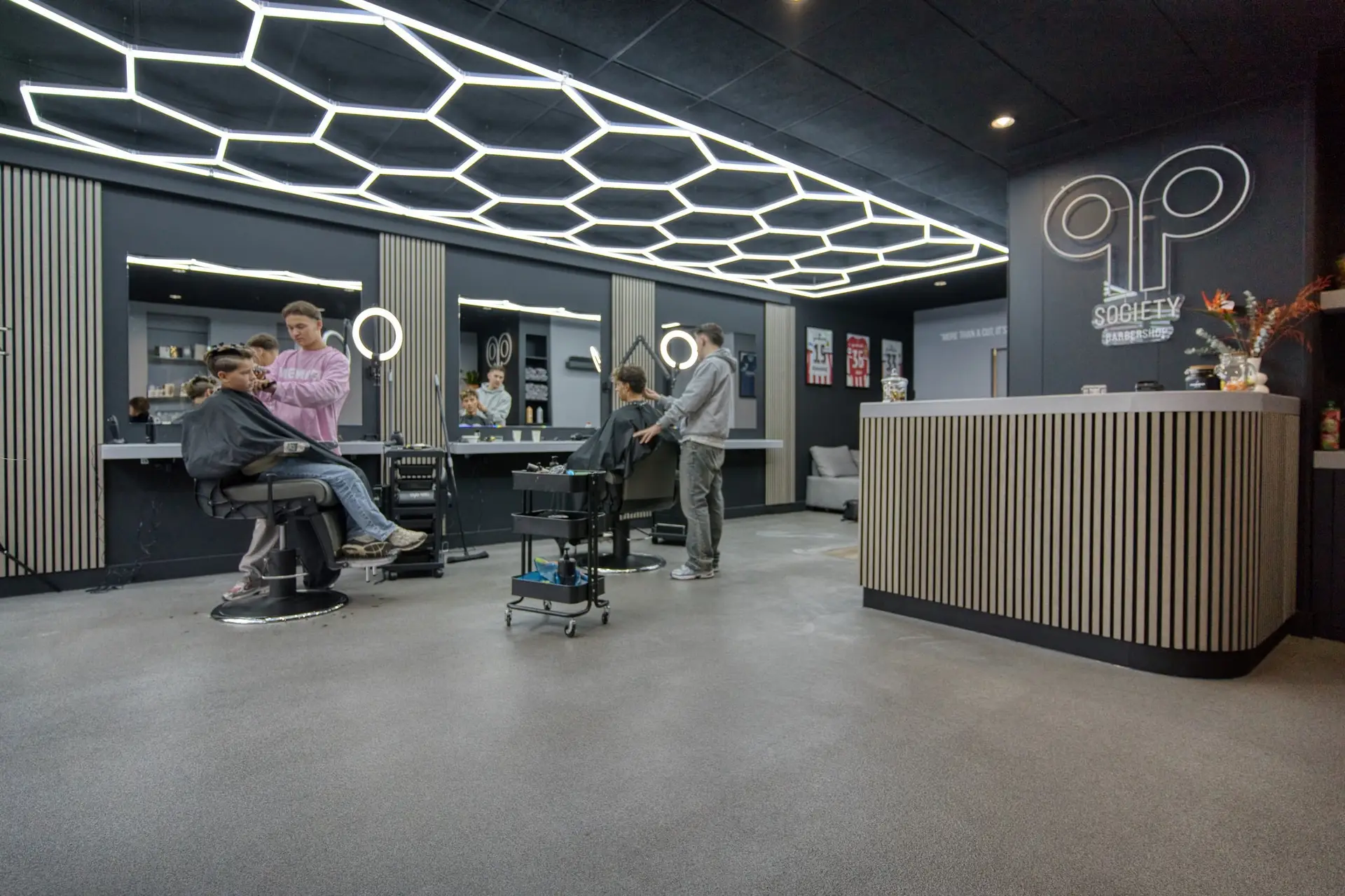 De zaak van QP Society: stoelen onder het honingraatplafond, de houten balie en het neonlogo